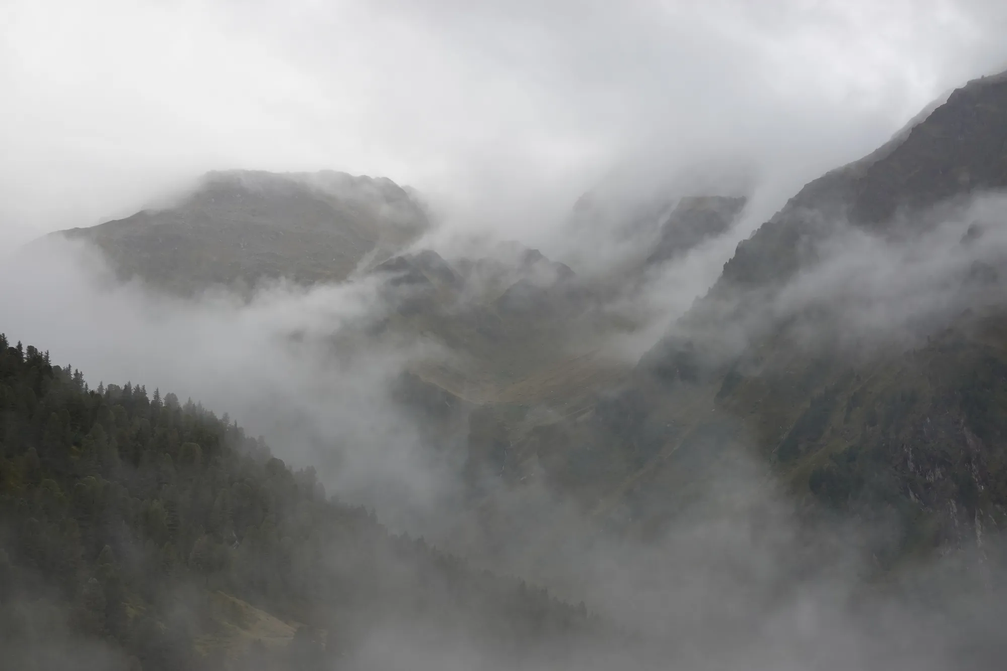 Nebel und tief hängende Wolken am Morgen über den Bergen