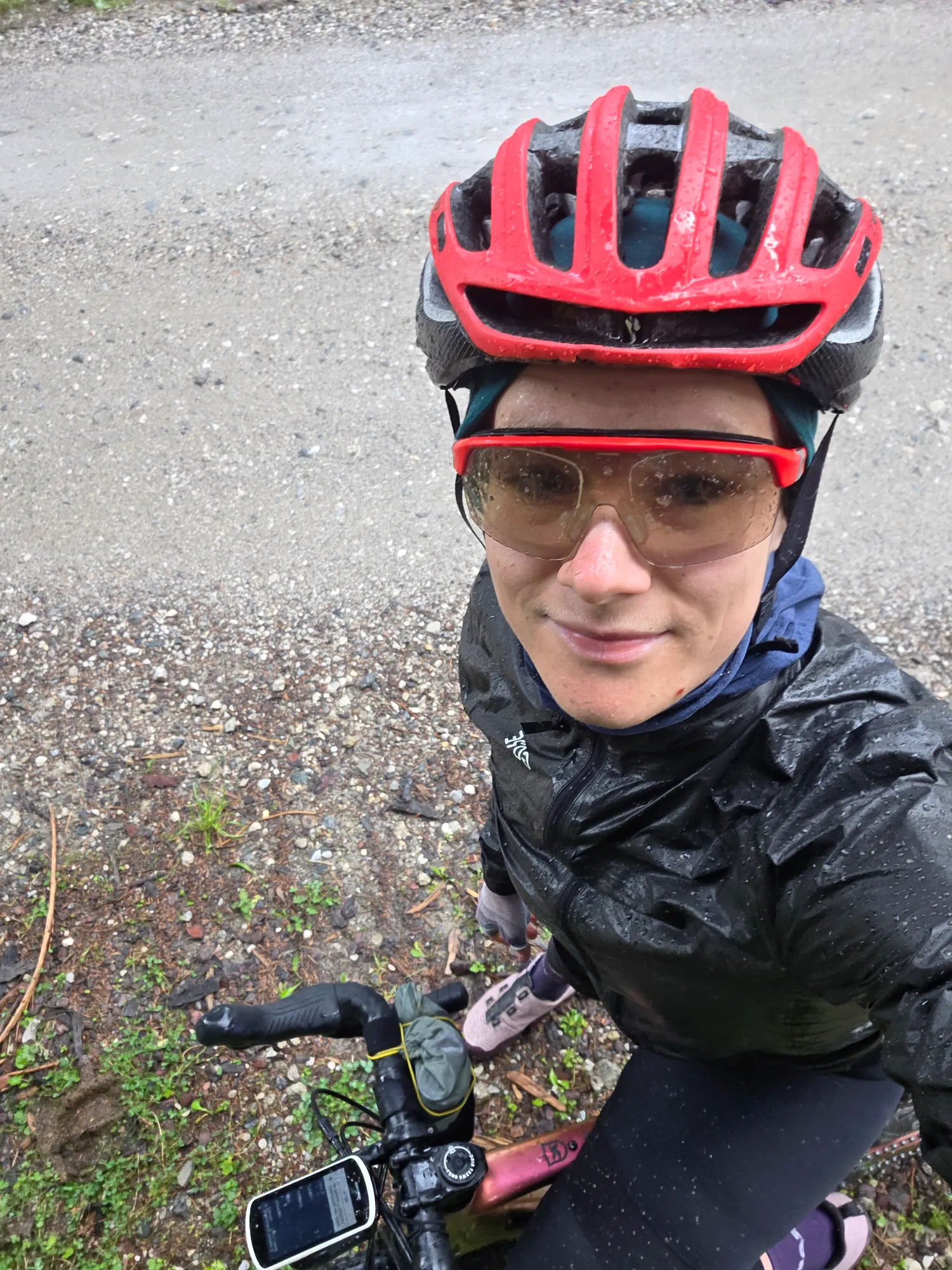 Carla in Regenjacke und rotem Helm auf dem Gravelbike