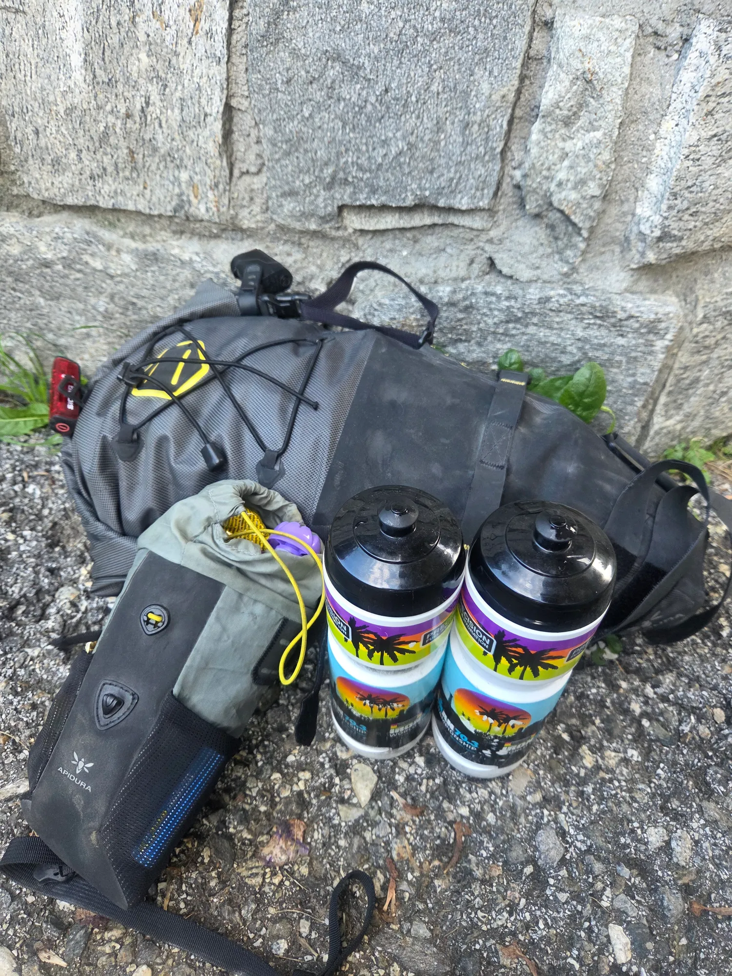 Gepackte Bikepacking-Taschen und zwei Trinkflaschen an einer Steinmauer