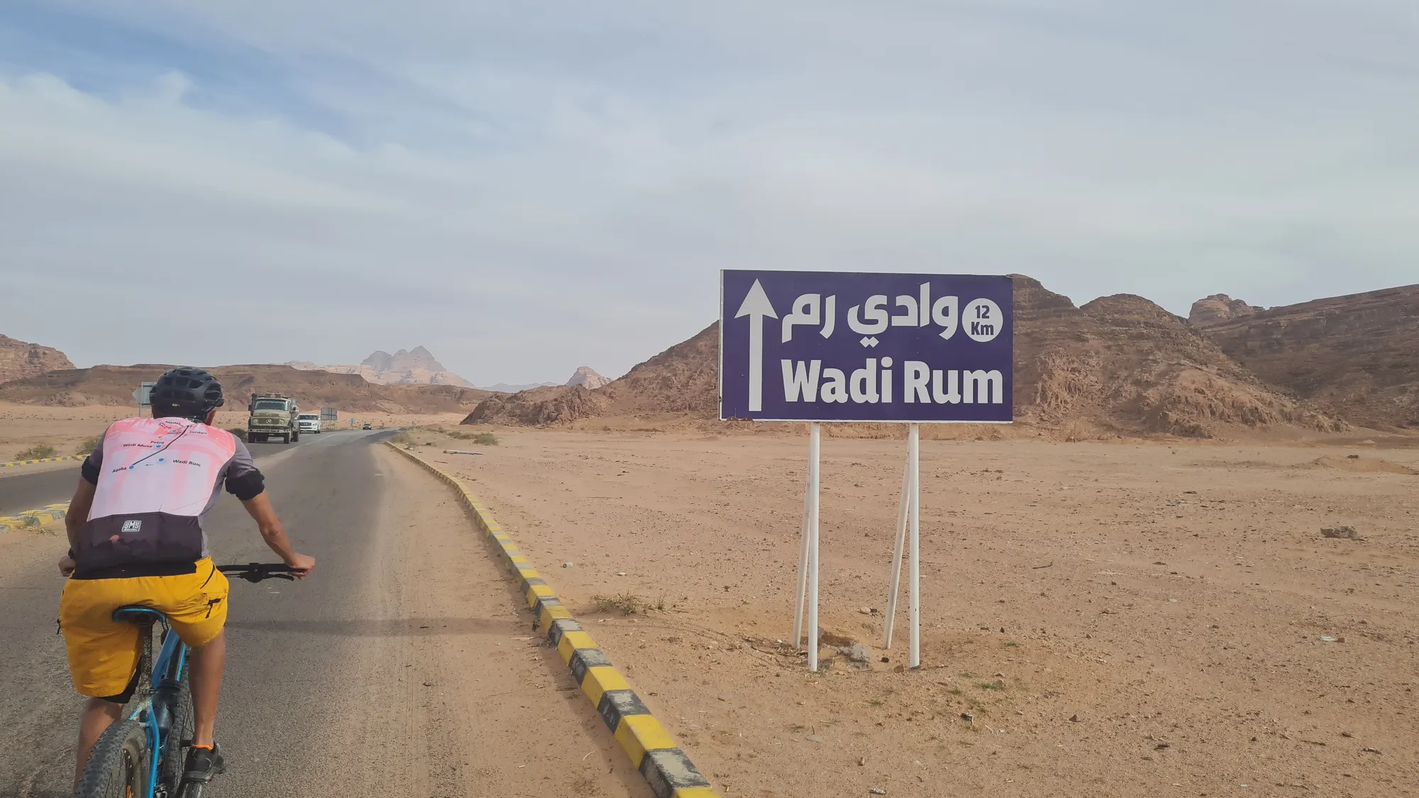 Radfahrerin am Schild nach Wadi Rum