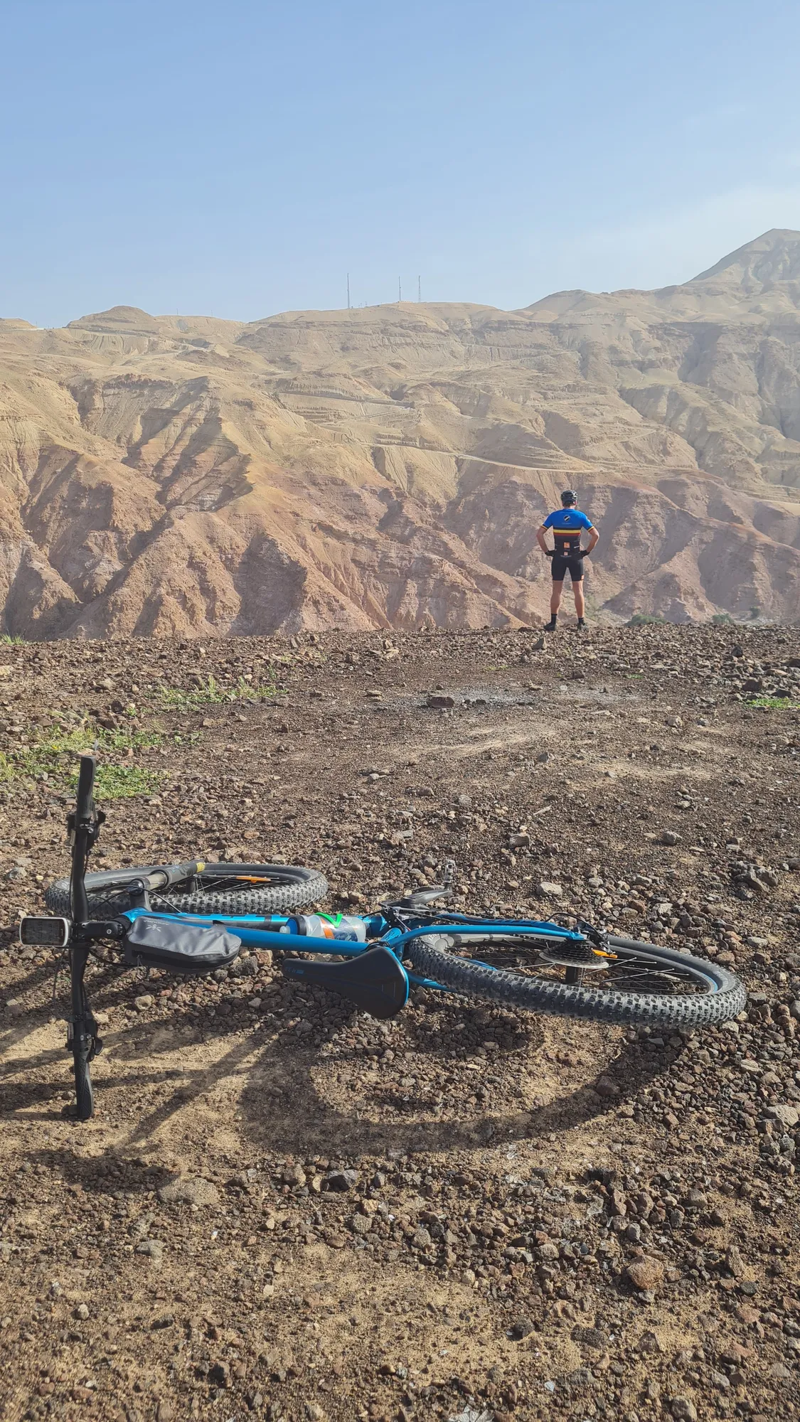 Mountainbike am Boden, dahinter jemand aus der Gruppe vor bunten, zerklüfteten Bergen