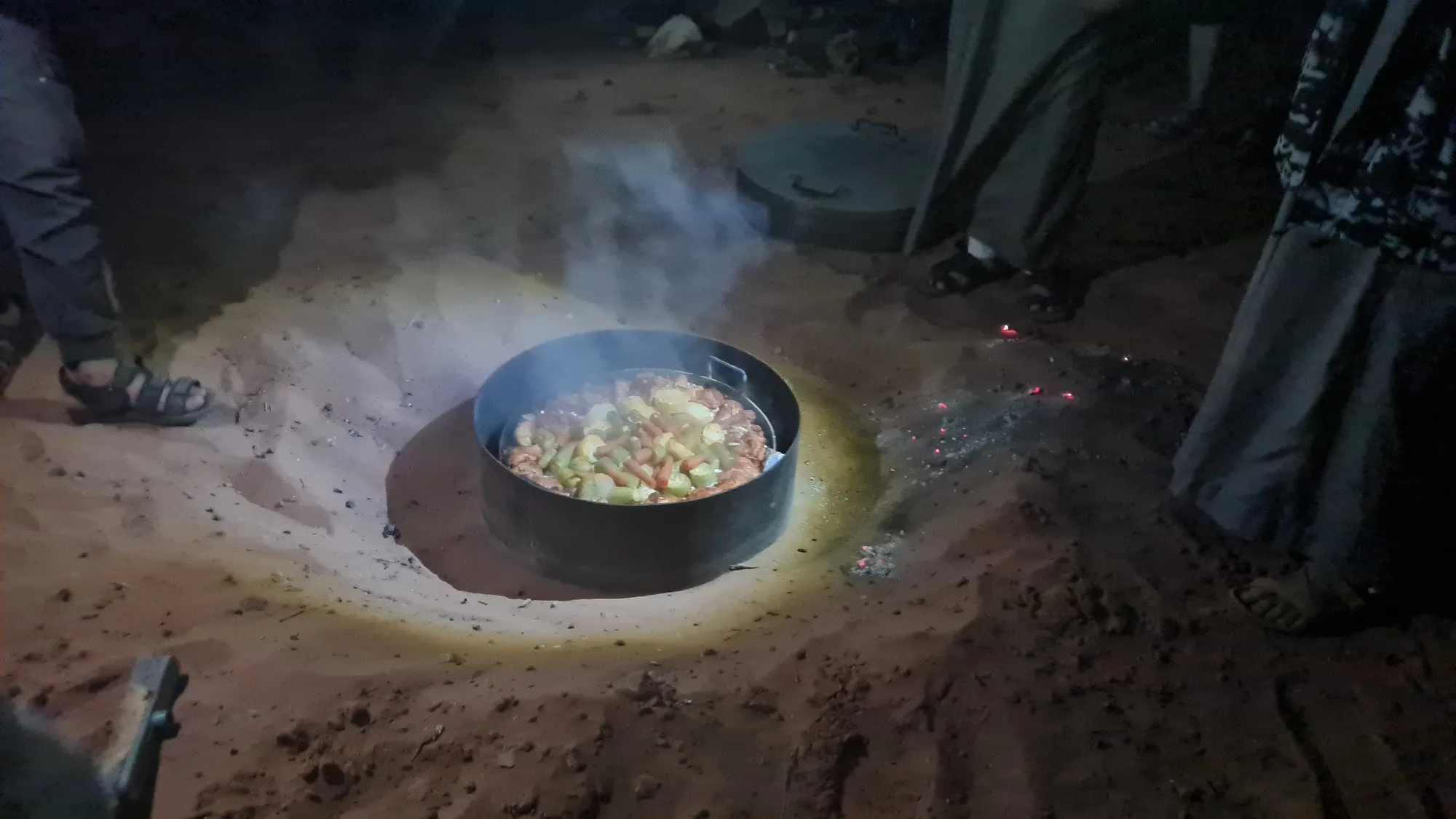 Abendessen im Wüstencamp: ein Topf in einer Grube im Sand