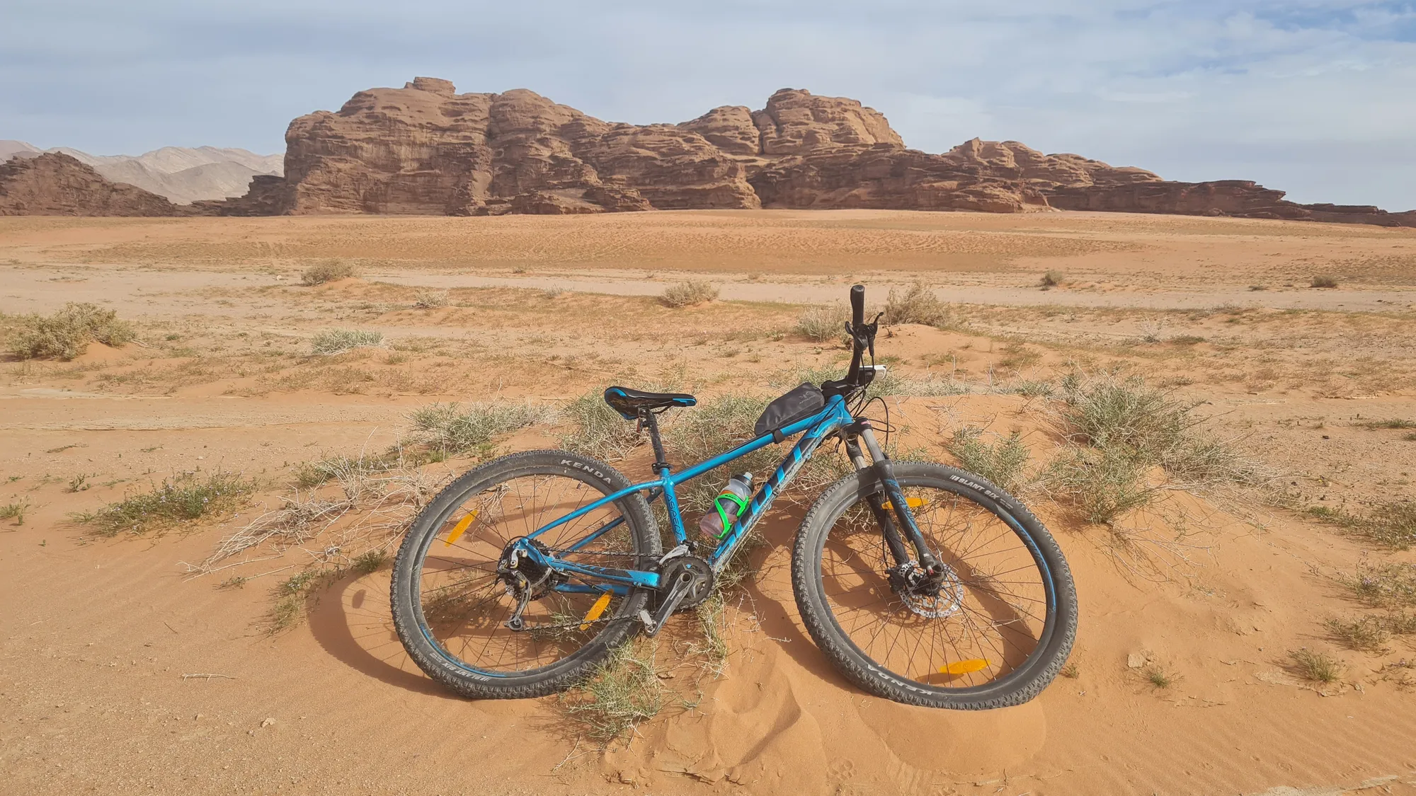 Mountainbike im roten Sand vor den Felsen des Wadi Rum