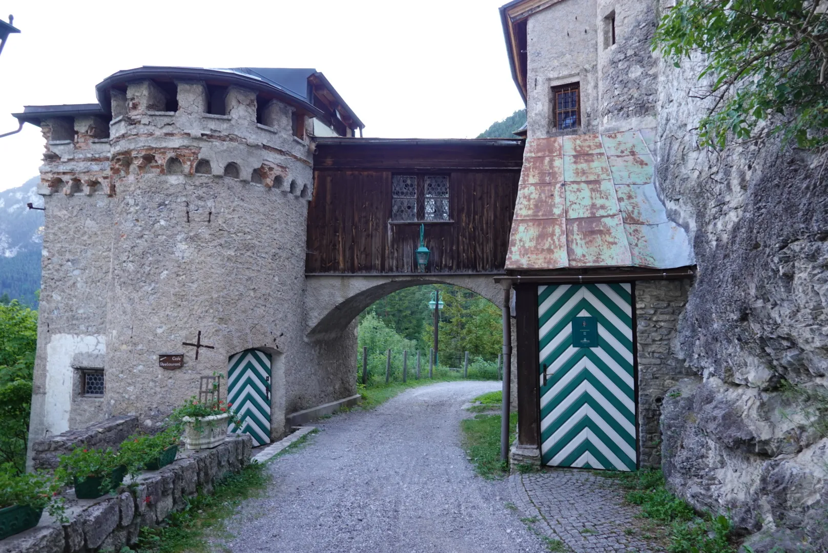 Gravelweg durch das steinerne Torhaus mit Turm und grün-weiß gestreiften Türen