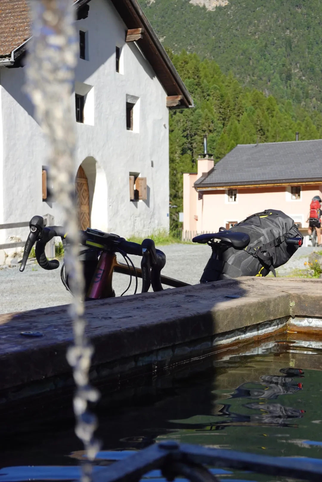 Morgens am Dorfbrunnen in S-charl, das Rad lehnt am Trog