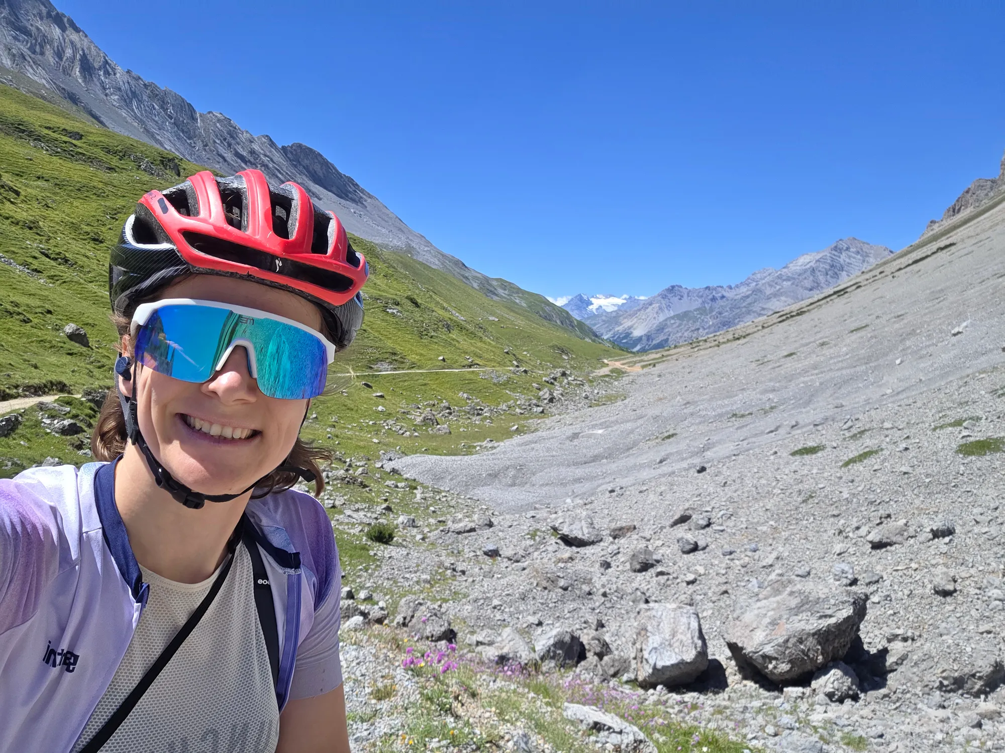 Carla mit rotem Helm und Sonnenbrille vor einem Geröllhang