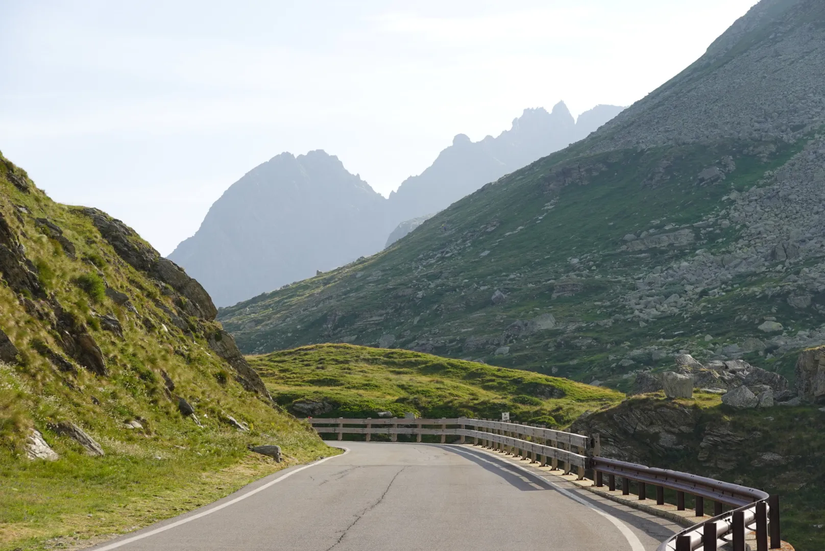 Passstraße schlängelt sich durch grüne Hänge zum Splügenpass