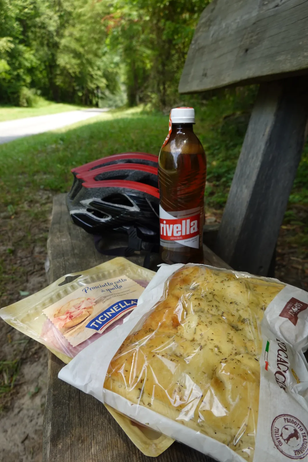 Picknick auf einer Holzbank: Rivella, Helm und Proviant