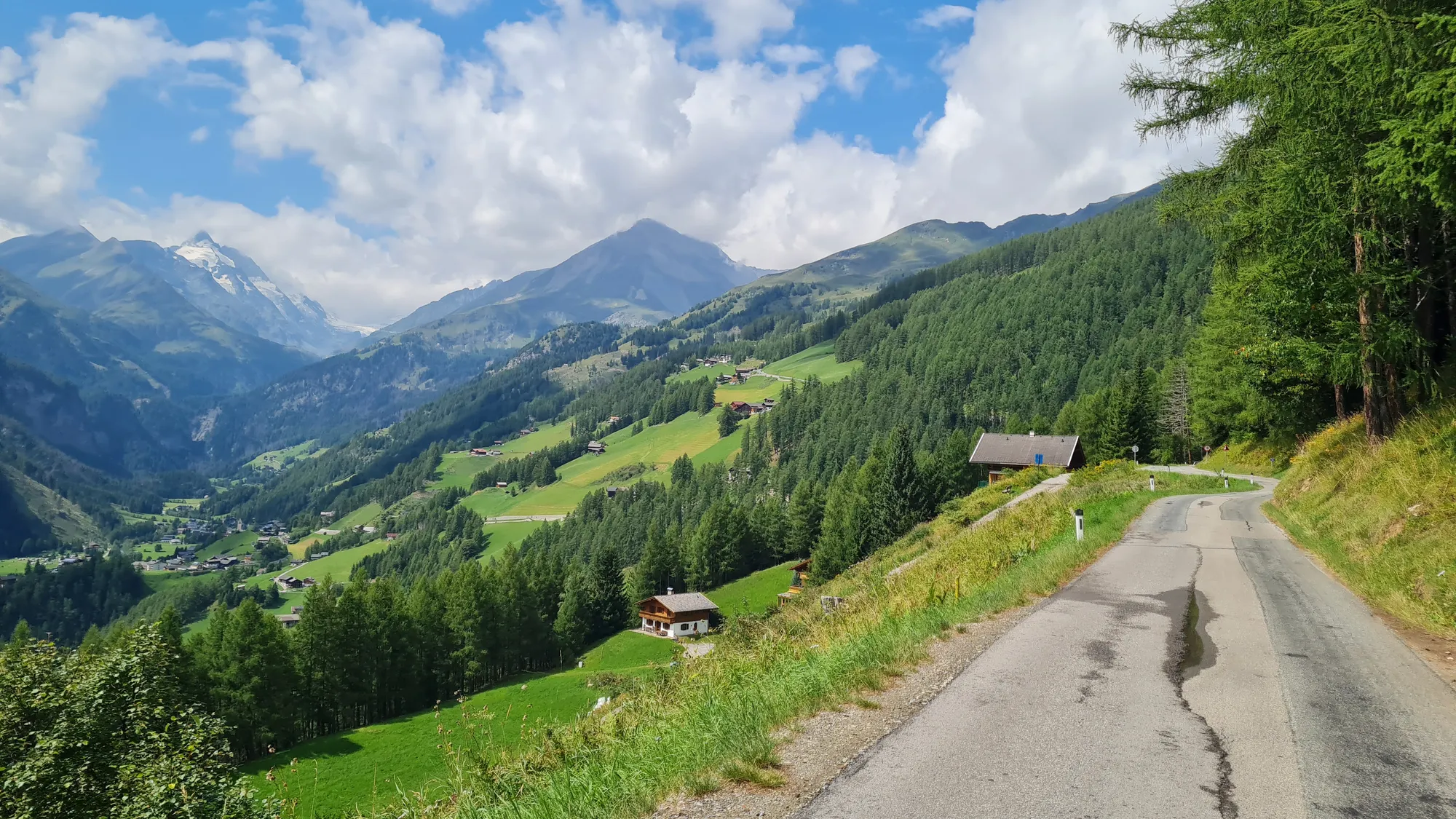 Schmale Straße mit Blick ins grüne Tal und auf die Hohen Tauern