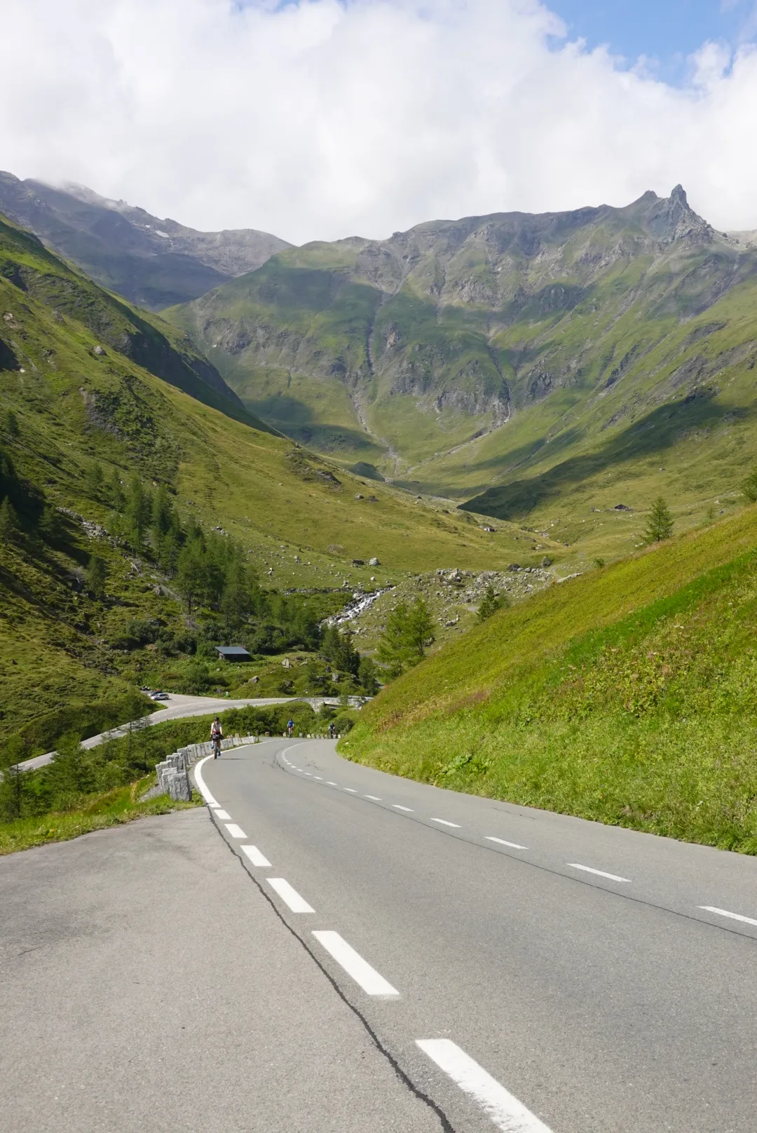 Die Hochalpenstraße zieht sich durch ein grünes Hochtal nach oben