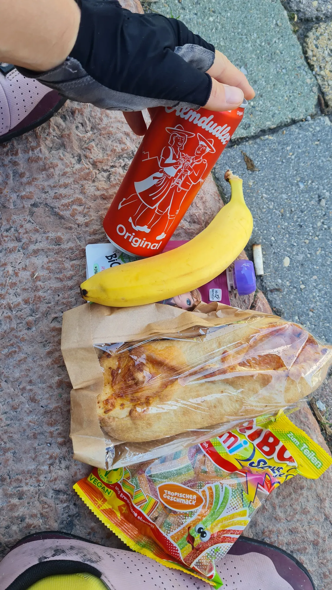 Proviant auf dem Asphalt: Gummibärchen, Sandwich, Banane und eine Dose Almdudler