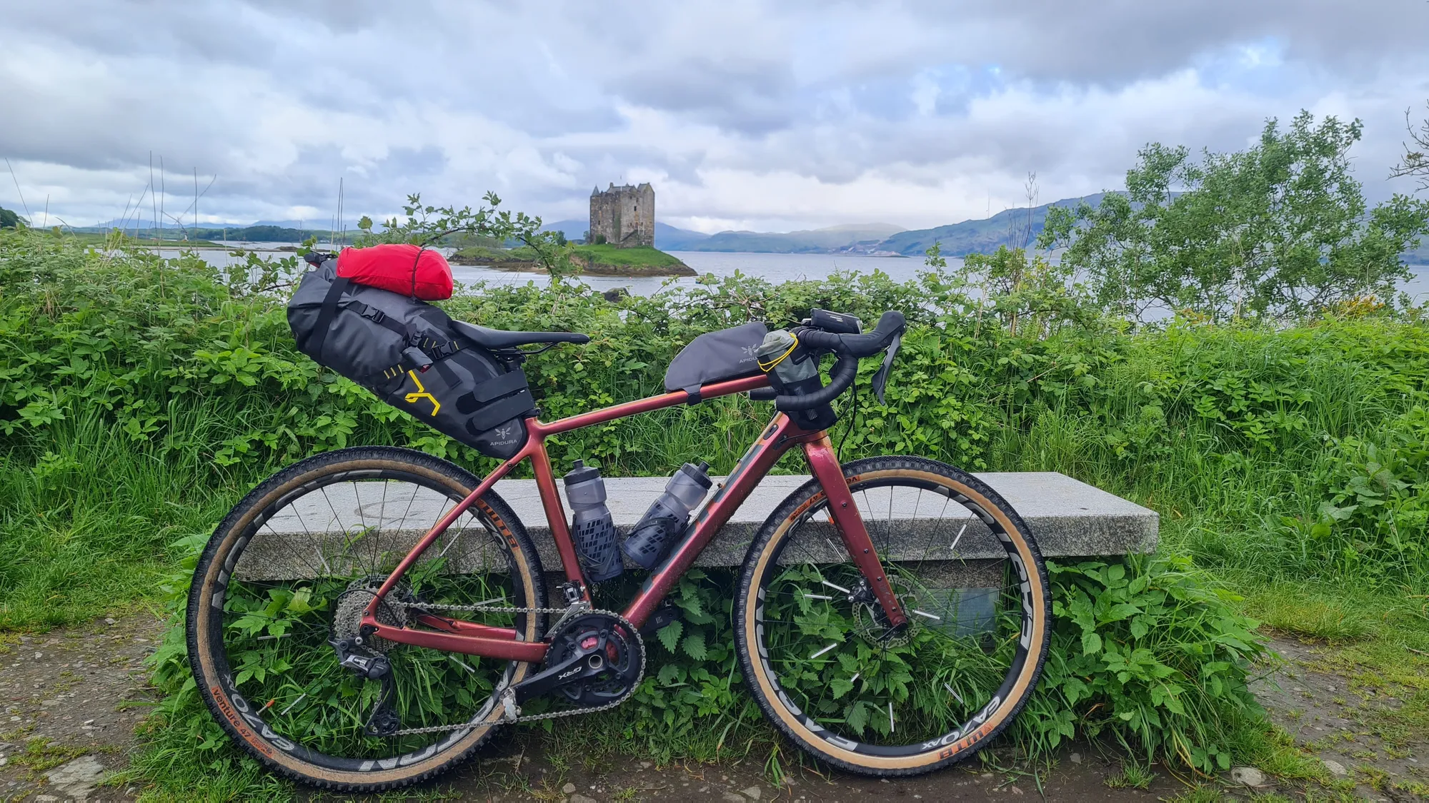 Bepacktes Gravelbike an einer Bank, im Hintergrund Castle Stalker
