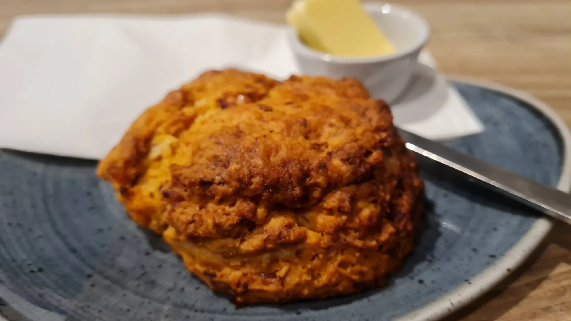 Ein Scone mit Butter auf einem Teller