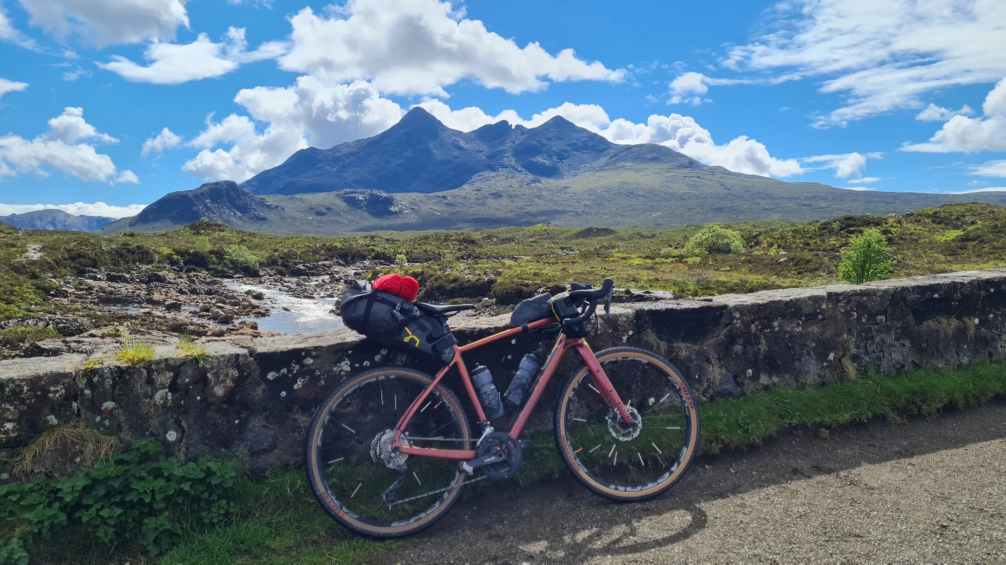 Bepacktes Gravelbike an einer Steinmauer vor den Cuillin-Bergen auf Skye