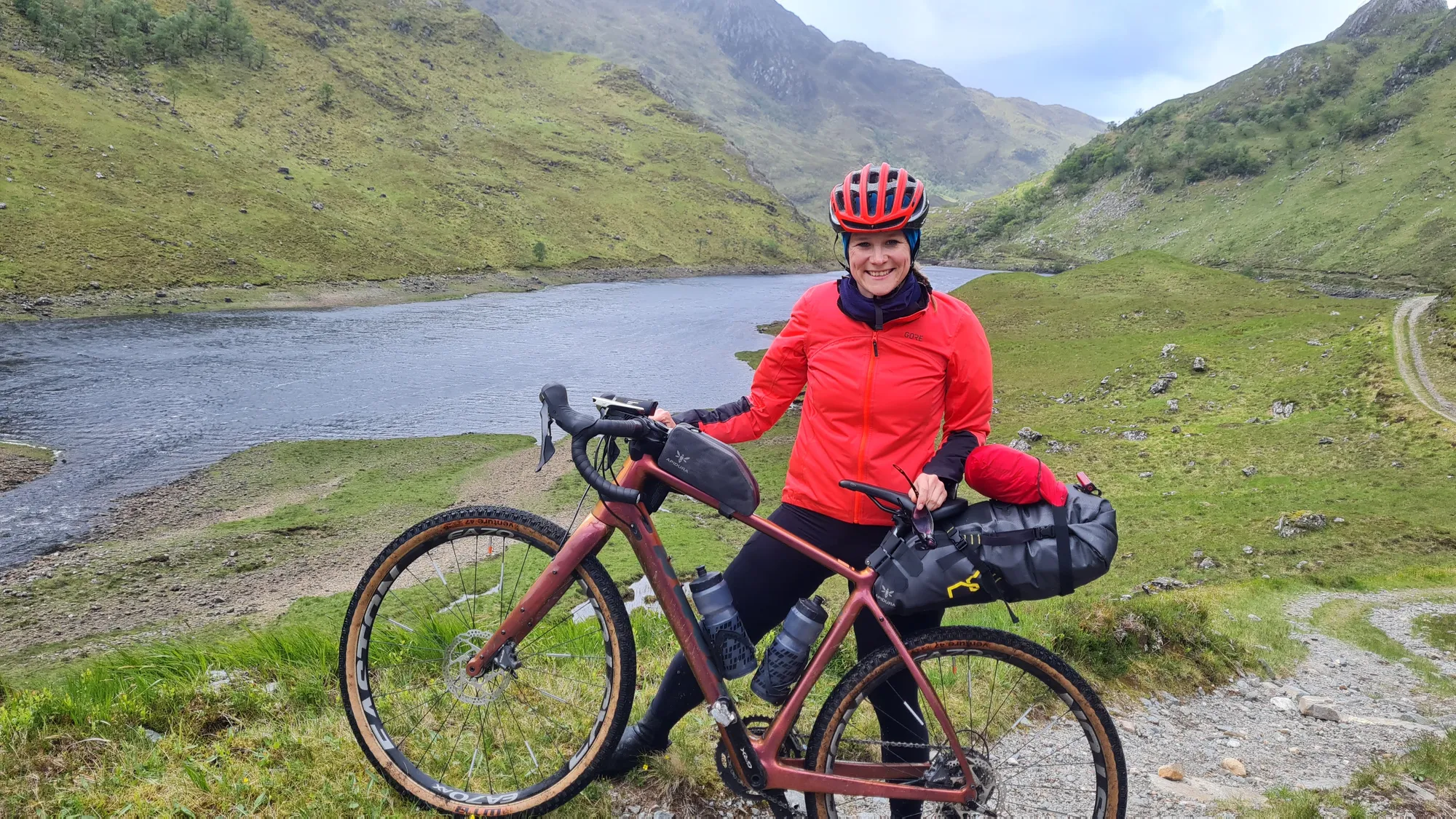 Carla mit dem Rad über dem Loch, ein Gravelweg schlängelt sich ins Tal