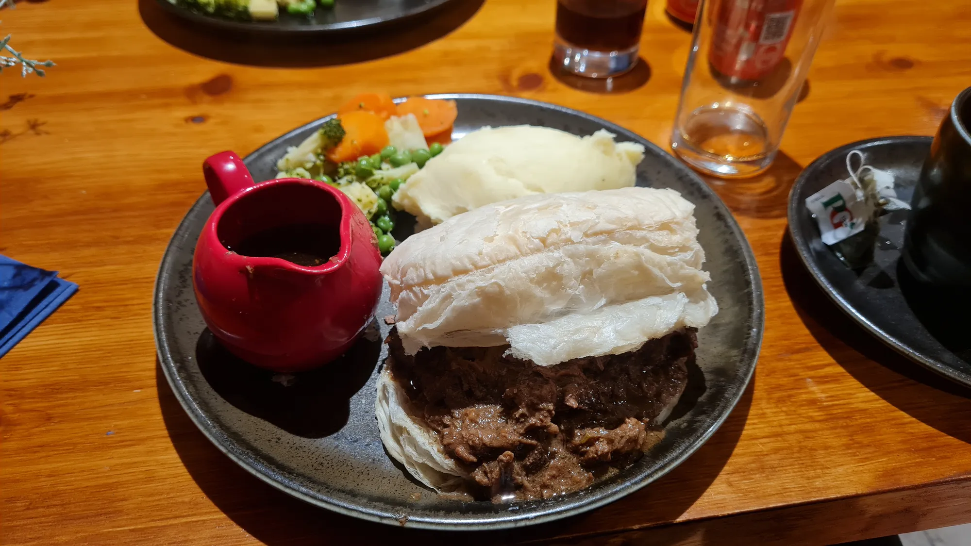 Pie mit Kartoffelbrei, Gemüse und einem Kännchen Soße