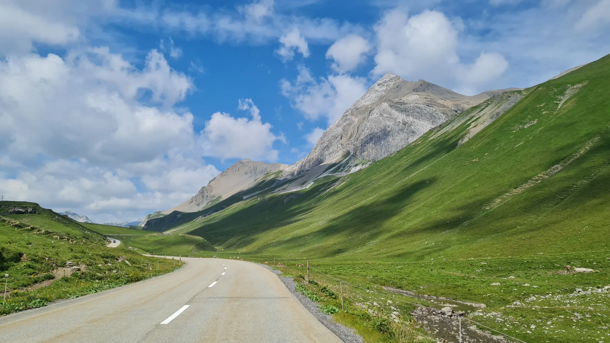 Leere Straße durch grüne Wiesen hinauf zum Albulapass