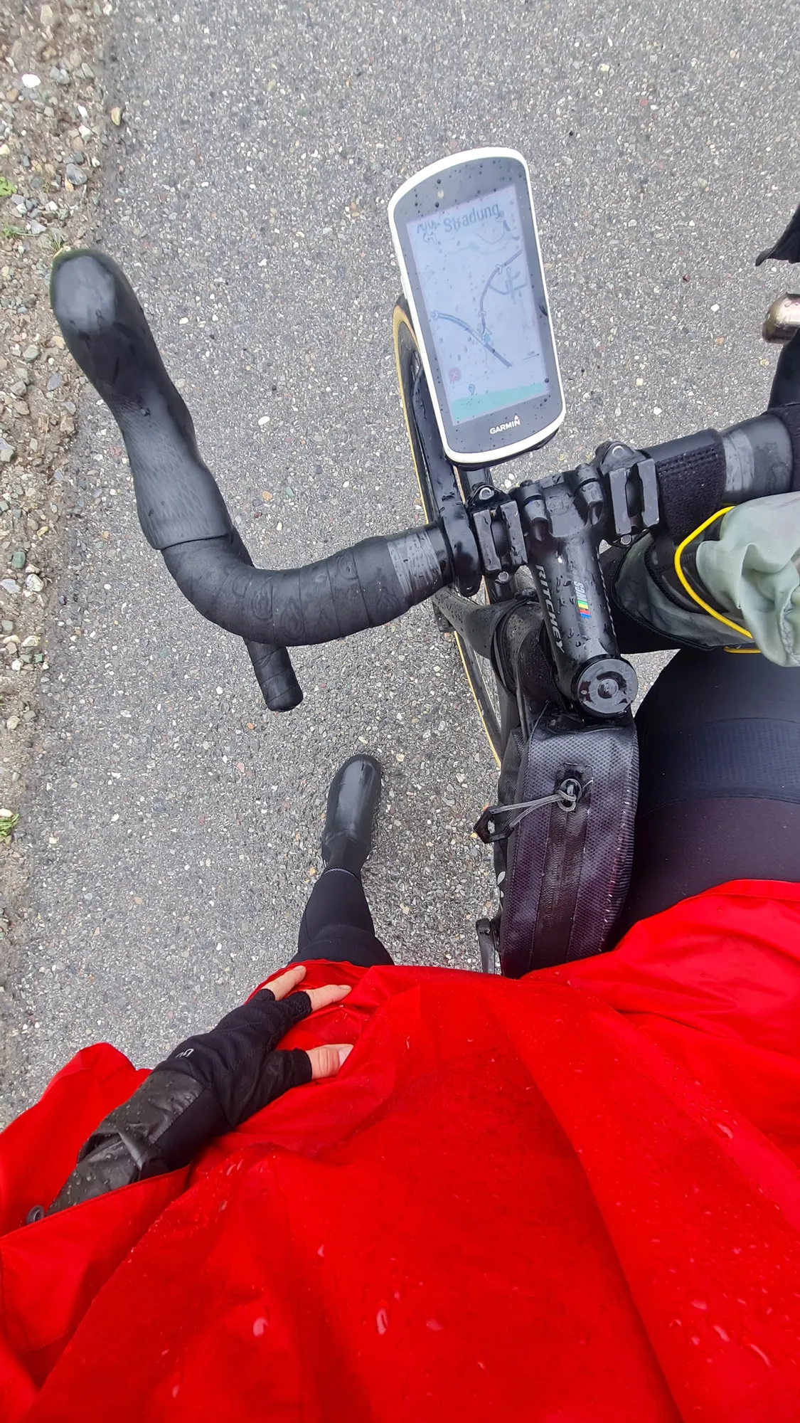 Roter Regenponcho und nasser Lenker mit Radcomputer