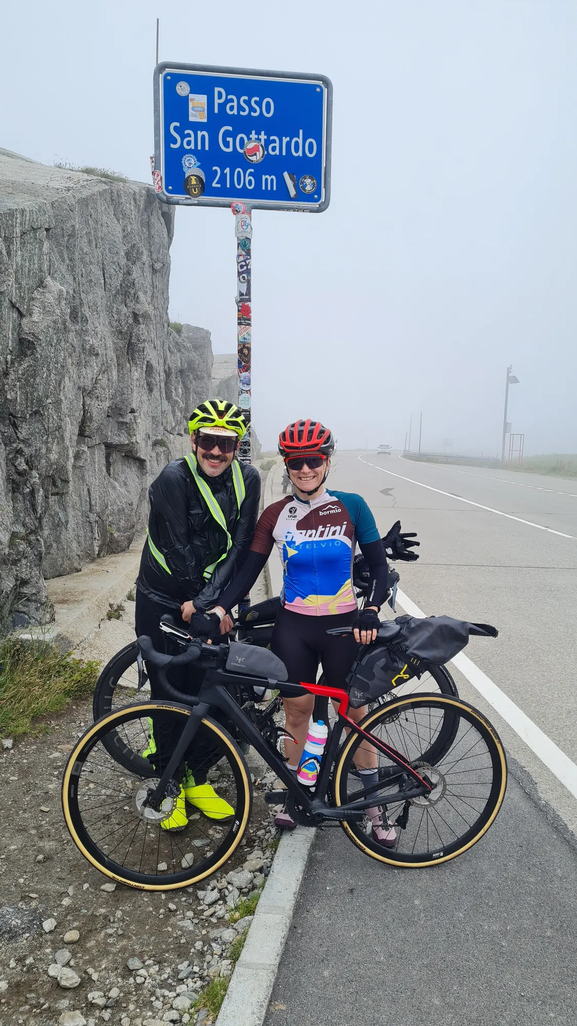 Zu zweit am Schild Passo San Gottardo, 2106 m, im Nebel
