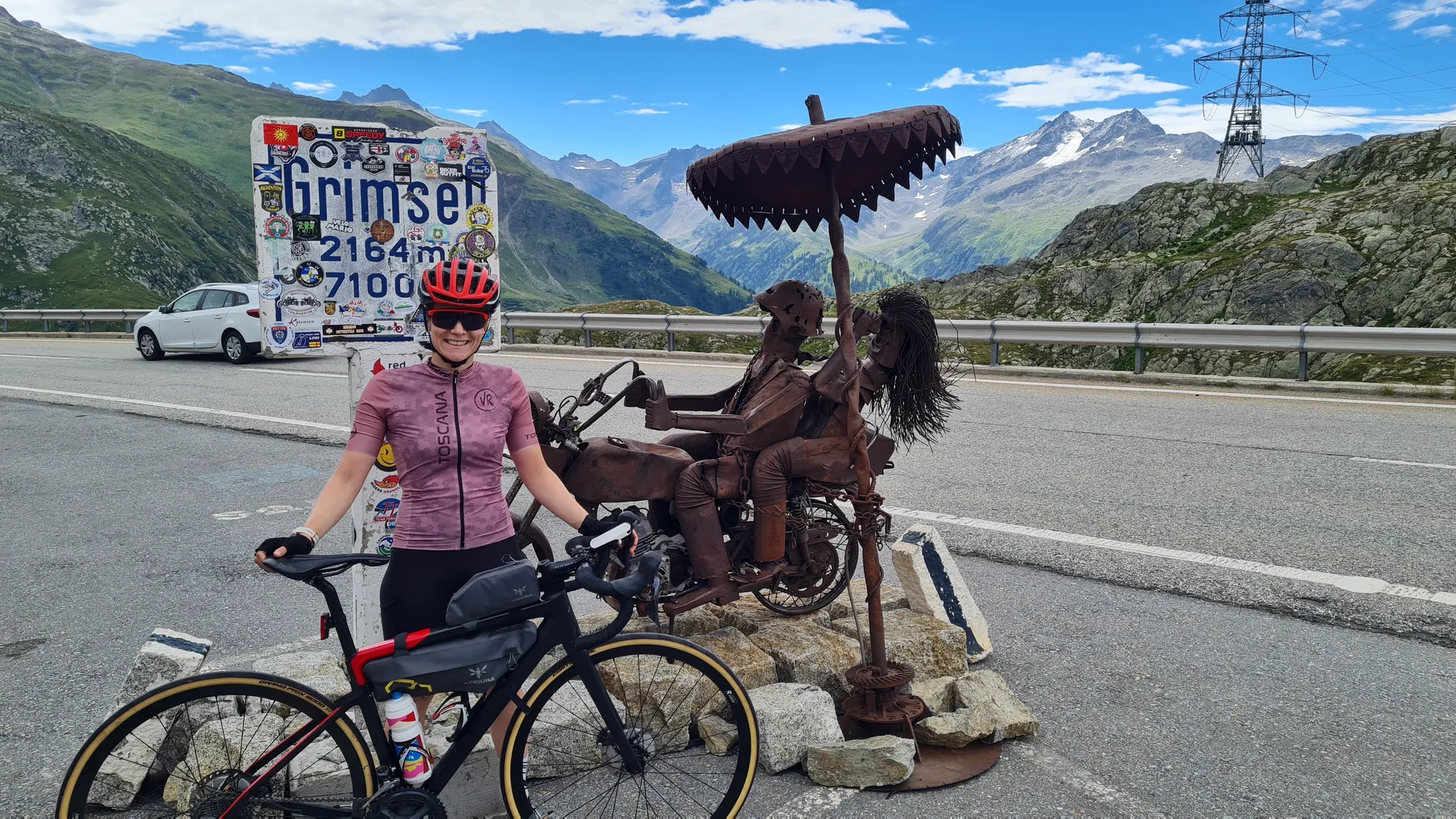 Am Schild Grimselpass, 2164 m, neben einer Metallskulptur
